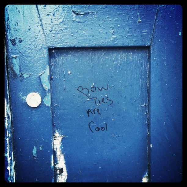 Faded door of a blue Glasgow Police Box with "Bow ties are cool" written on it